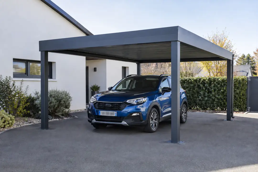 Carport aluminium anthracite à toiture plate abritant un SUV devant une maison récente