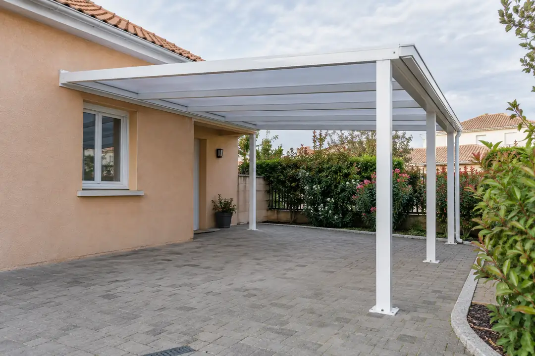 Carport aluminium blanc adossé à une façade ocre, couverture translucide