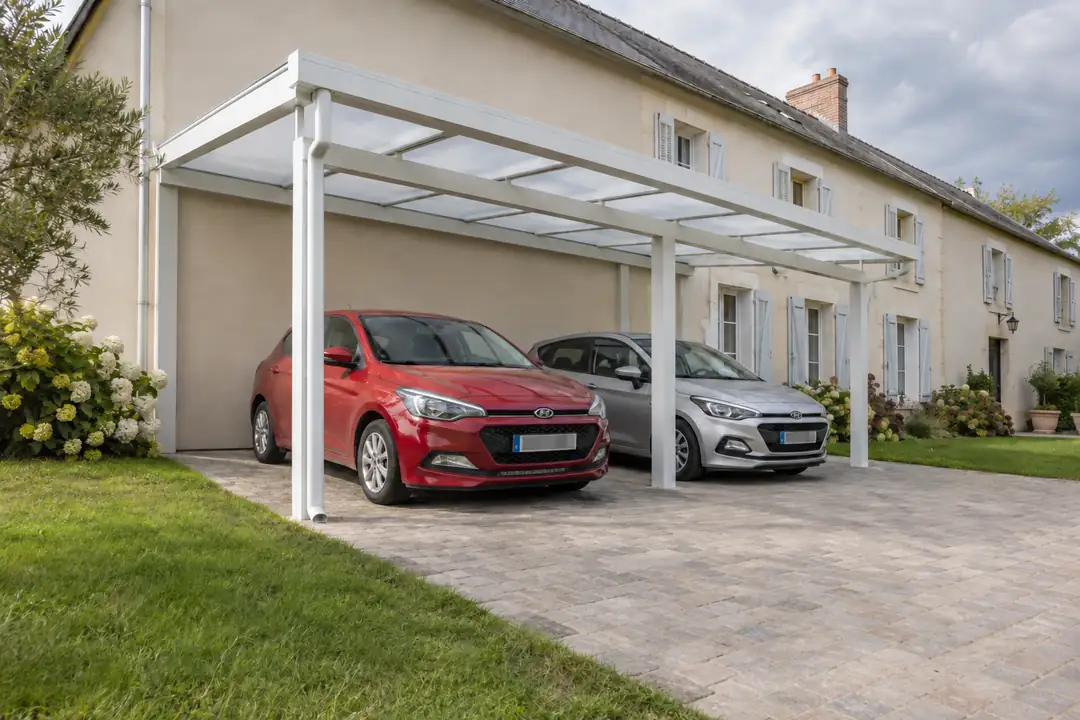 Carport double adossé blanc à couverture translucide abritant deux voitures